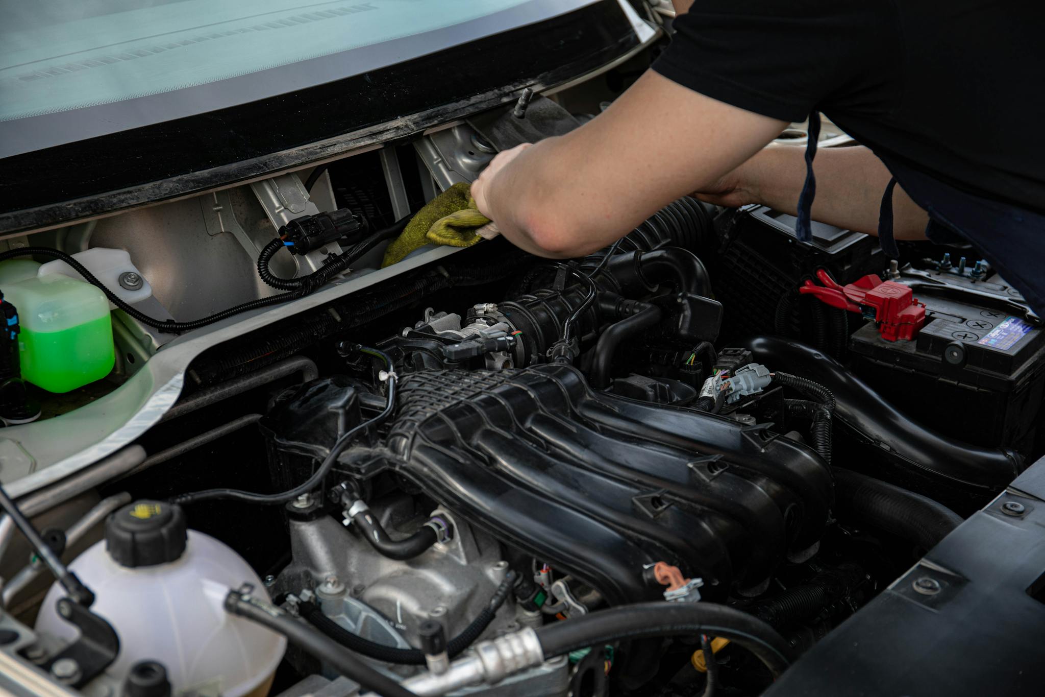Close-up of a mechanic working on a car engine in a workshop setting.