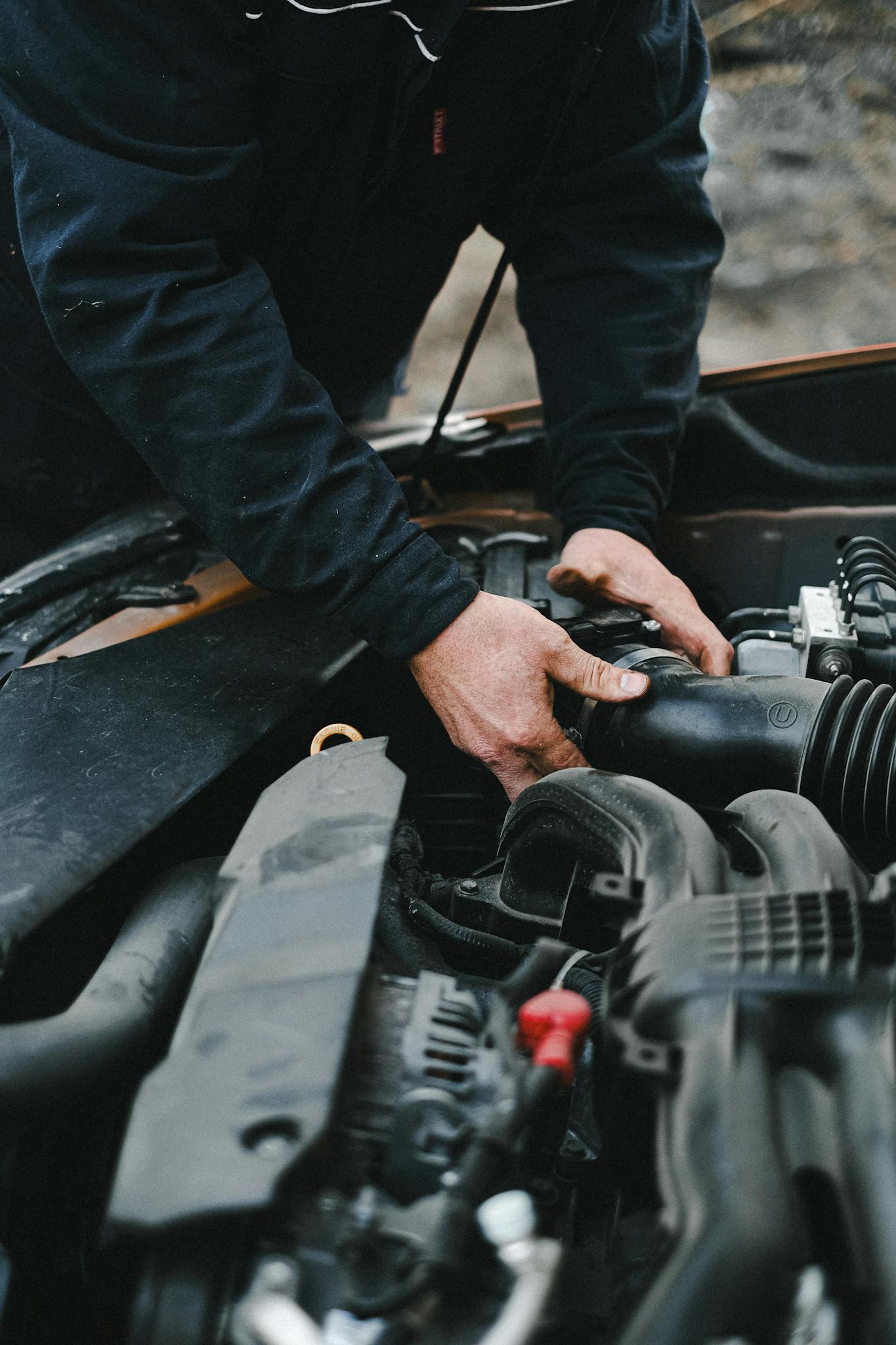 Close-up of a mechanic's hands working on a car engine inside a workshop.