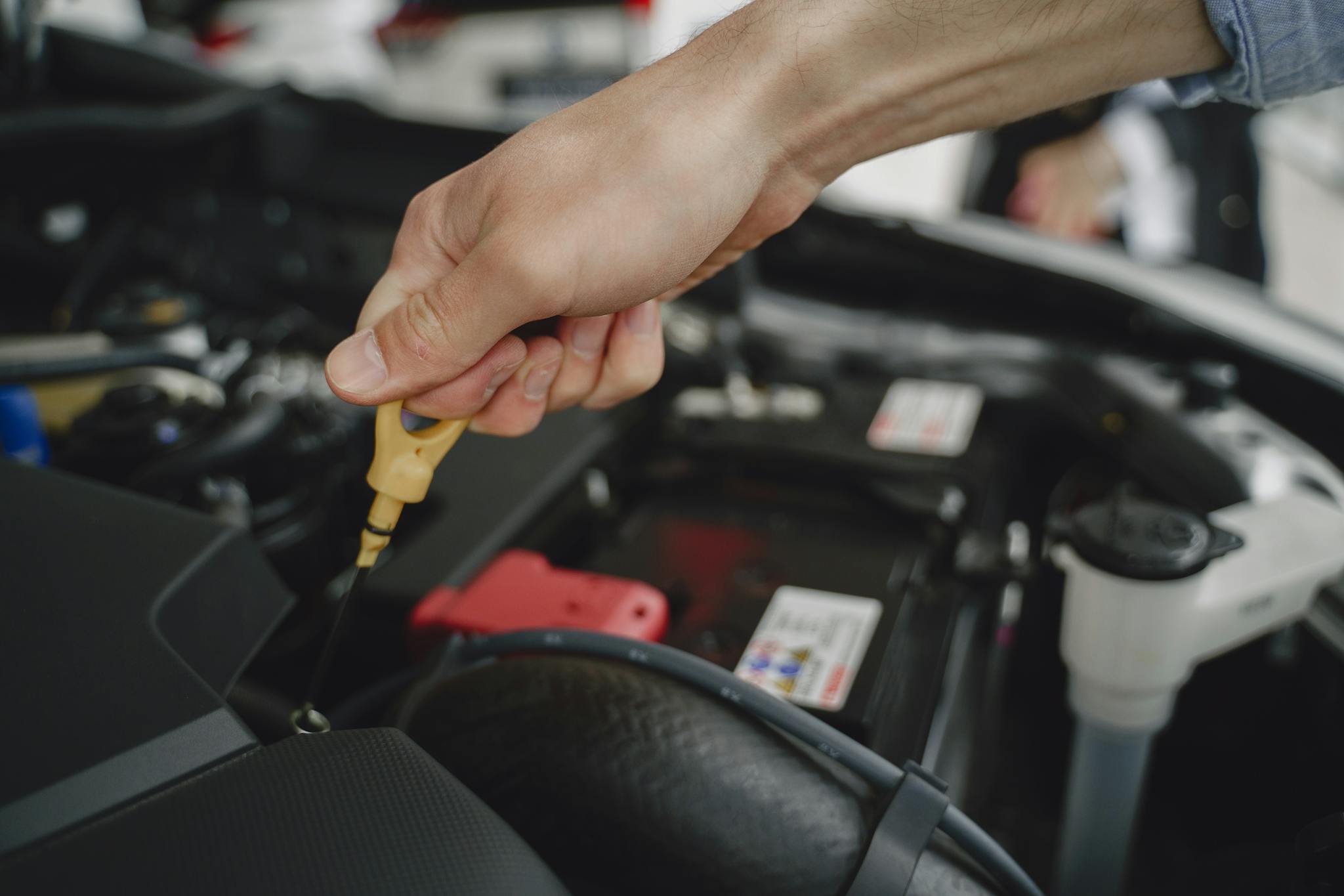 Hand checking oil dipstick in a car engine bay for maintenance and diagnostics.